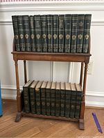 Front view of vintage wooden table displaying a collection of hardcover books; shows the top shelf and the structure of the table.