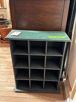 Front angle view of the wooden wall display shelf showing its 3 by 5 compartment grid and top surface.