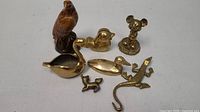 Top-down view of the 7 brass and brown patina figurines showing all shapes and sizes including hawk, duck, swan, lizard and small animals.