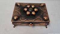 Top view of the copper metal trinket box showing raised circular dome decorations on the lid in a symmetrical pattern.