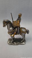 Side view of the pewter medieval knight figurine on horse showing detailed armor and shield with gold accents.