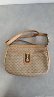 Front view of beige Gucci purse with GG monogram, leather trim and iconic web stripe with metal GG charm.