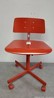 Front view of red vintage swivel office chair with wooden seat and backrest, metal frame and casters