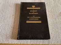 Front cover of hardcover black book titled 'A Journey to Katmandu' with gold embossed text and decoration.