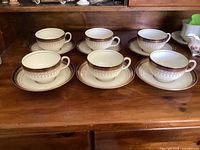 Full set of six porcelain cups each with a matching saucer, displayed on wooden surface, showing uniform design and very good condition.