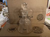 Photo showing the antique clear glass vinegar bottle with faceted stopper on top, front view, highlighting the ribbed textured lower half and handle.