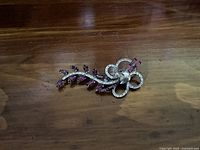 Front view of Bond Boyd sterling silver brooch with purple marquise-shaped gemstones on wooden surface