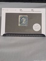 Single blue Canadian postage stamp with profile of Queen Victoria, mounted visible on gray display card with label markings.