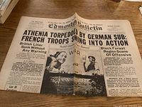 Single front page of Edmonton Bulletin newspaper laid open on table, showing headlines about Athenia torpedoed by German submarine and wartime events.