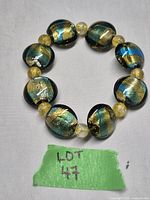 Photo of the entire stretch bracelet displaying large oval multicolored glass beads and smaller round yellow beads on elastic cord.