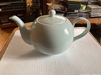 Side view of the white ceramic Royal Doulton Gordon Ramsay Maze teapot with lid on, showing the curved spout, handle and round body.