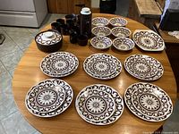 Full set of dinnerware on table including plates, bowls, cups, coffee pot, creamer, sugar bowl, platter, and casserole dishes.