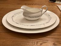 Set of two oval platters (15.25 inches and 13.25 inches) with a matching gravy boat placed on wooden surface, showing the decorative pattern.