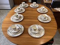 Full view of the 8 place settings arranged on a dining table, showing cups, saucers, and plates stacked by size.