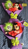 Two Beetlejuice Valentine's Day themed plush bouquets, wrapped in purple felt with green bow, showing Beetlejuice and Lydia characters holding red plush hearts.