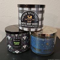 Three Bath & Body Works candles - Pumpkin Spice Latte, Wicked Apple, and Blueberry Sleigh.