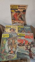 Photo showing a front view of six Classics Illustrated comic books: Western Stories with Jim Bowie, The Prince and the Pauper, The Virginian, The Jungle Book, and Typee.
