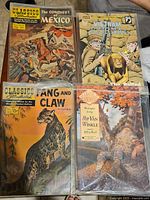 Four vintage comic books including Classics Illustrated The Conquest of Mexico, Vietnam Journal, Fang and Claw, and Rip Van Winkle.