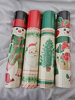 Four cylindrical vintage match containers with Christmas artwork including snowmen, Santa, and Christmas tree.