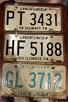 Three Illinois license plates from 1977 and 1978 with 'Land of Lincoln' text, showing wear and rust.