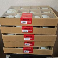 Four stacked cardboard boxes with red labels showing 'Wondershop Ornament Set' containing the ornaments.