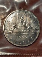 Front face of the 1969 Canadian Voyageur Dollar coin showing the canoe and voyageurs design.