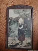 Full view of the antique framed artwork with scrolled wood arched frame on a wood floor taken from the front.