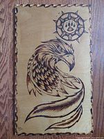 Wood engraved wooden plaque with scalloped edges depicting an eagle and bear paw symbol in circular sun emblem, signed and dated 2016 D.S.