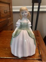 Front view of the Royal Doulton figurine showing the young girl in a pink and green dress with detailed facial features.