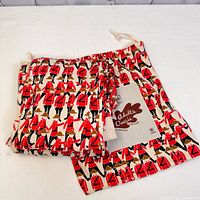 Drawstring carry bag with red RCMP Mountie print, laid flat to show pattern and brand label.