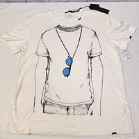 Full view of white T-shirt laid flat showing black line art design with blue sunglasses graphic on front