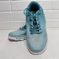 Pair of teal blue Propet women's running shoes on white background, front angled view