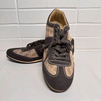 Pair of Guess men's casual shoes size 12, showing right shoe angled front and side view on white surface with white brick background.