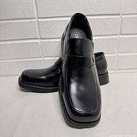 Pair of Kenneth Cole Unlisted black men's dress shoes shown at an angle to display shape and condition.