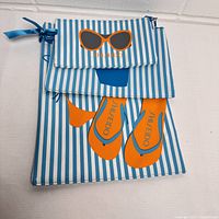 Three Shiseido branded beach bags with a blue and white stripe pattern, featuring orange flip-flops and sunglasses on the largest bag