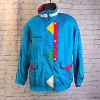 Full frontal view of blue color block windbreaker with red, yellow, green and white geometric accents.