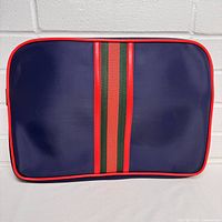 Front side of vintage American Industries portfolio bag showing navy blue material, red trim, and green-red-green vertical stripes.