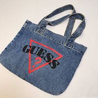Full view of the blue denim tote bag with Guess logo and two shoulder straps.
