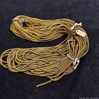 Vintage long golden braided metal rope laid in coils and tied with string on black background.