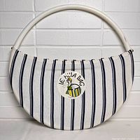 Front view of the round hula hoop bag purse showing white fabric with vertical navy stripes and the attached original tag.