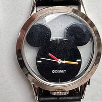 Close up of the Mickey Mouse silhouette watch face with red, white, and yellow hands and Disney text