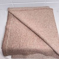 Folded fabric showing texture and pattern in pink and beige woven wool.