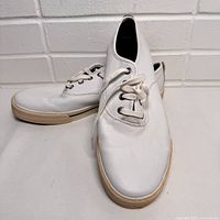 Left shoe angled view showing white exterior with light creases and off-white sole.