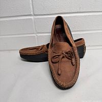 Side angle view of brown leather women's deck boat shoes showing moccasin-style stitching and lace details on top.