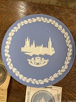 Blue 1974 Wedgwood Christmas plate with raised white design of Trafalgar Square and Lord Nelson, leaf border, on wooden surface