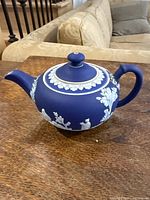 Side view of the Wedgwood jasperware teapot showing neoclassical white relief decoration on dark blue body.