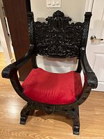 Frontal view of entire chair showing carved backrest and red velvet seat