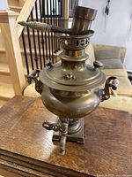 Front view of samovar on tabletop showing body, handles, spigot and base