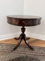 Front angle view of the vintage round mahogany drum table showing the single drawer and pedestal base.