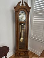 Front view of oak veneer grandfather clock with closed glass door
